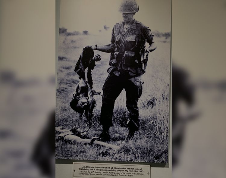 △ 一名士兵,手持着半截北越士兵的尸体,这一死者是被榴弹发射器炸死